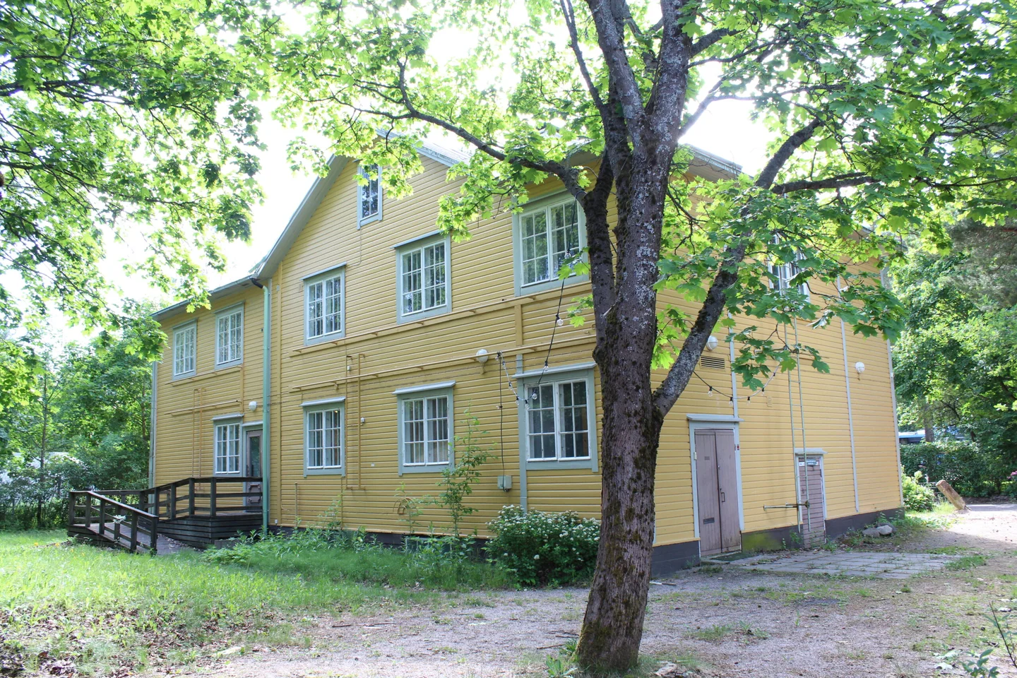 Helsingin Vanhan Mäntylän keltainen puujulkisivu ja puustoinen piha ennen peruskorjausta
